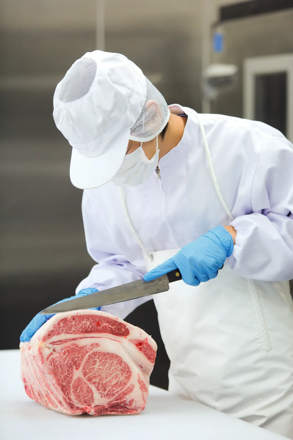 作業員が牛肉ブロックを包丁で整形する様子